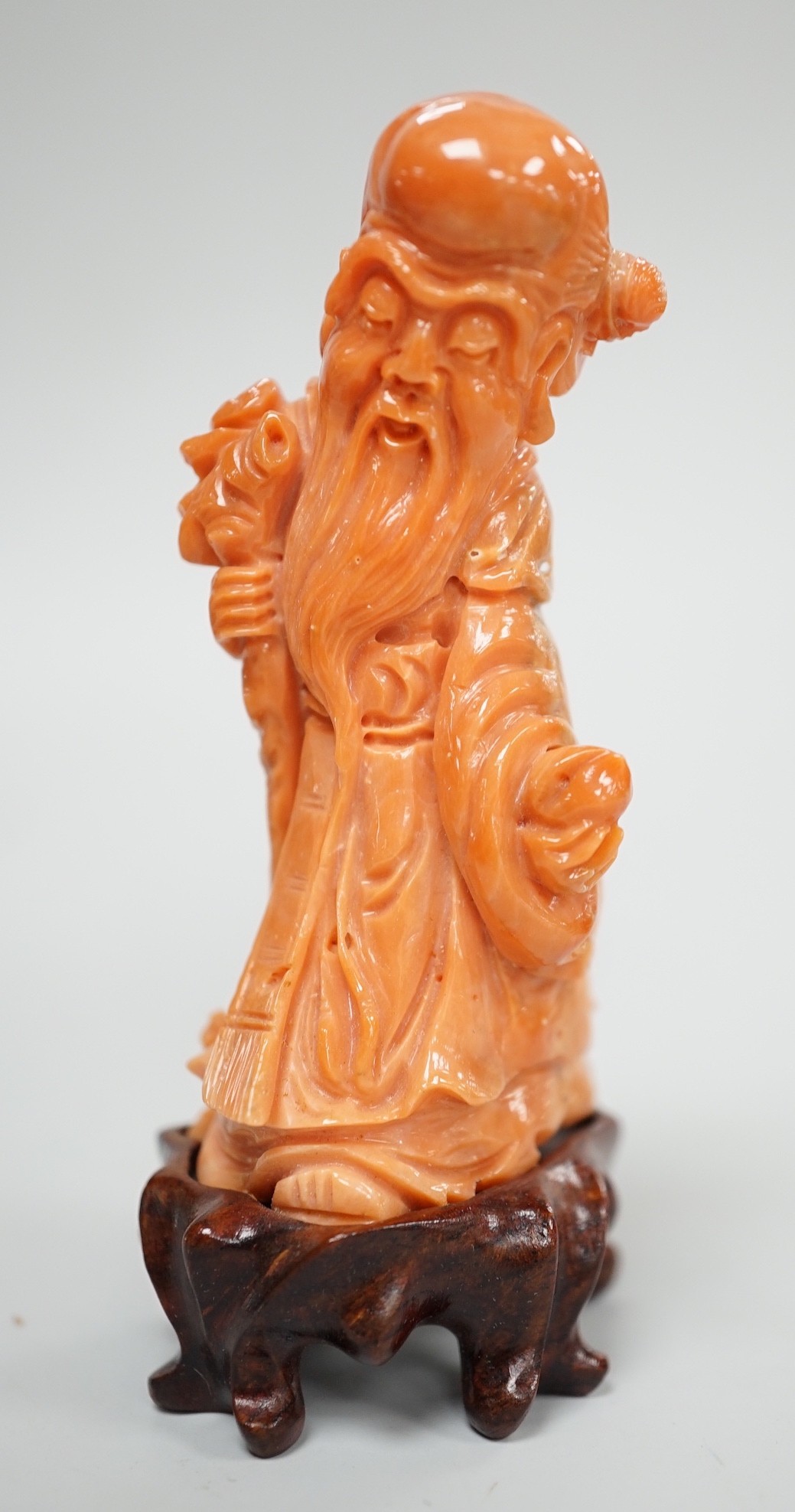 A Chinese coral figure of Shou Lao, 20th century, 7.4 cm high, 73g, wood stand